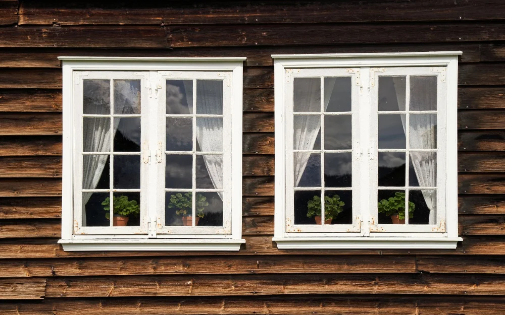Deux fenêtres en bois peintes en blanc sur une façade en bardage