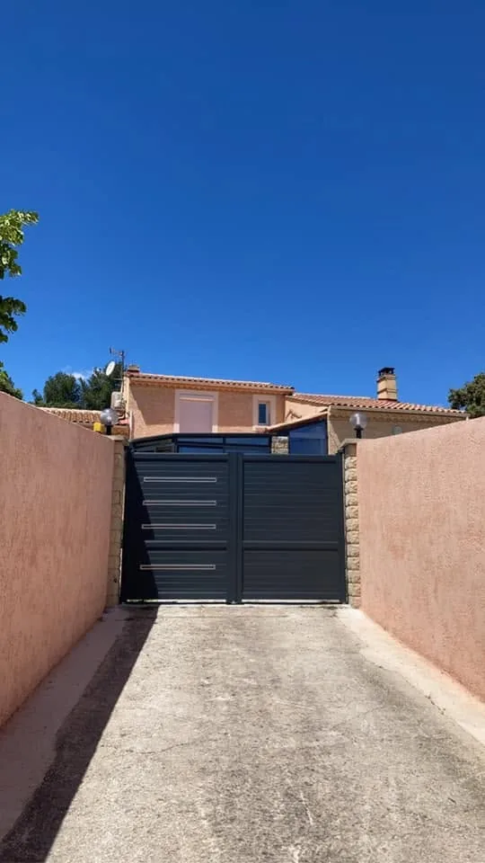 Portail aluminium anthracite au bout d'une allée de maison