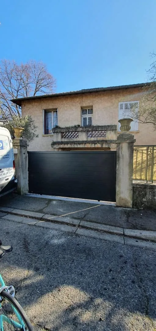 Portail coulissant aluminium noir le long d'un mur