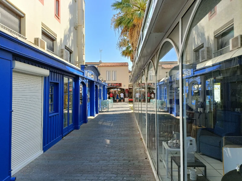 Rue commerçante avec rideaux métalliques et vitrines de magasins