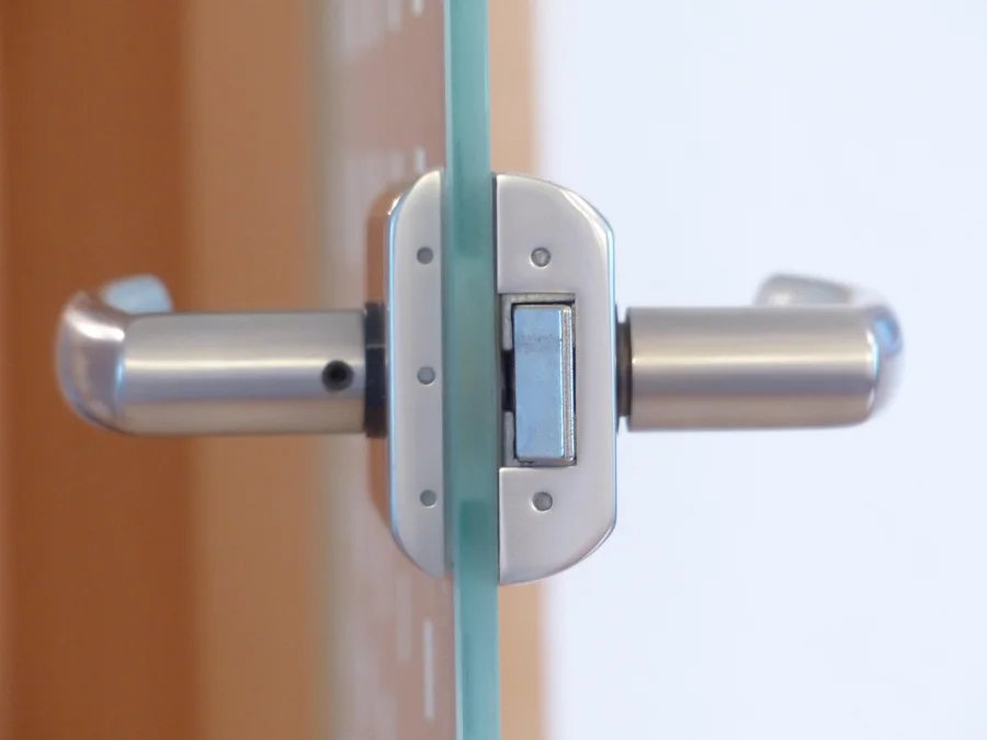 Serrure et poignée en inox sur une porte vitrée de commerce