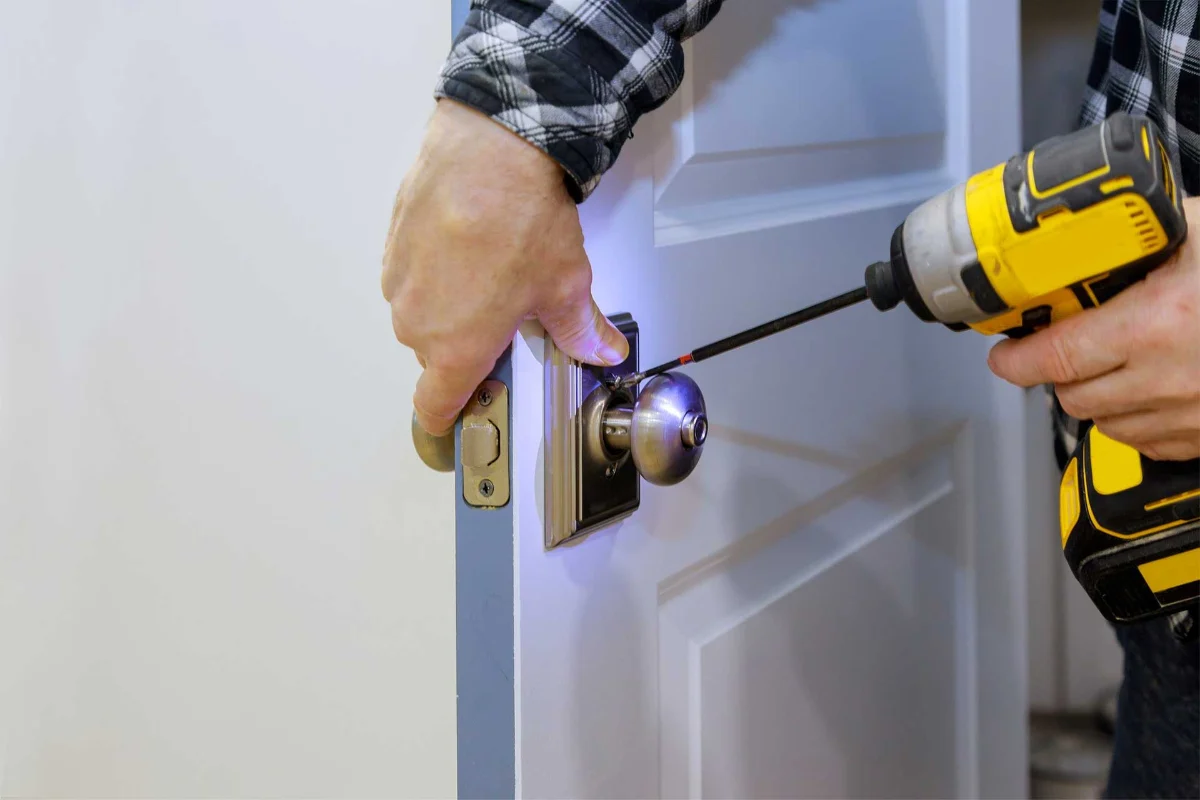 Serrurier vissant une serrure sur une porte