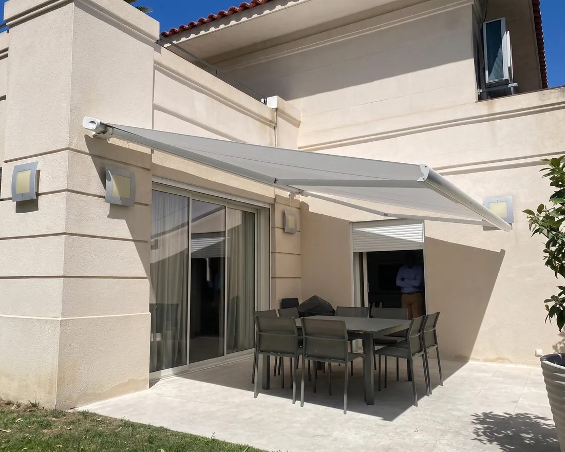 Terrasse abritée par un store banne, ouverte par une baie coulissante