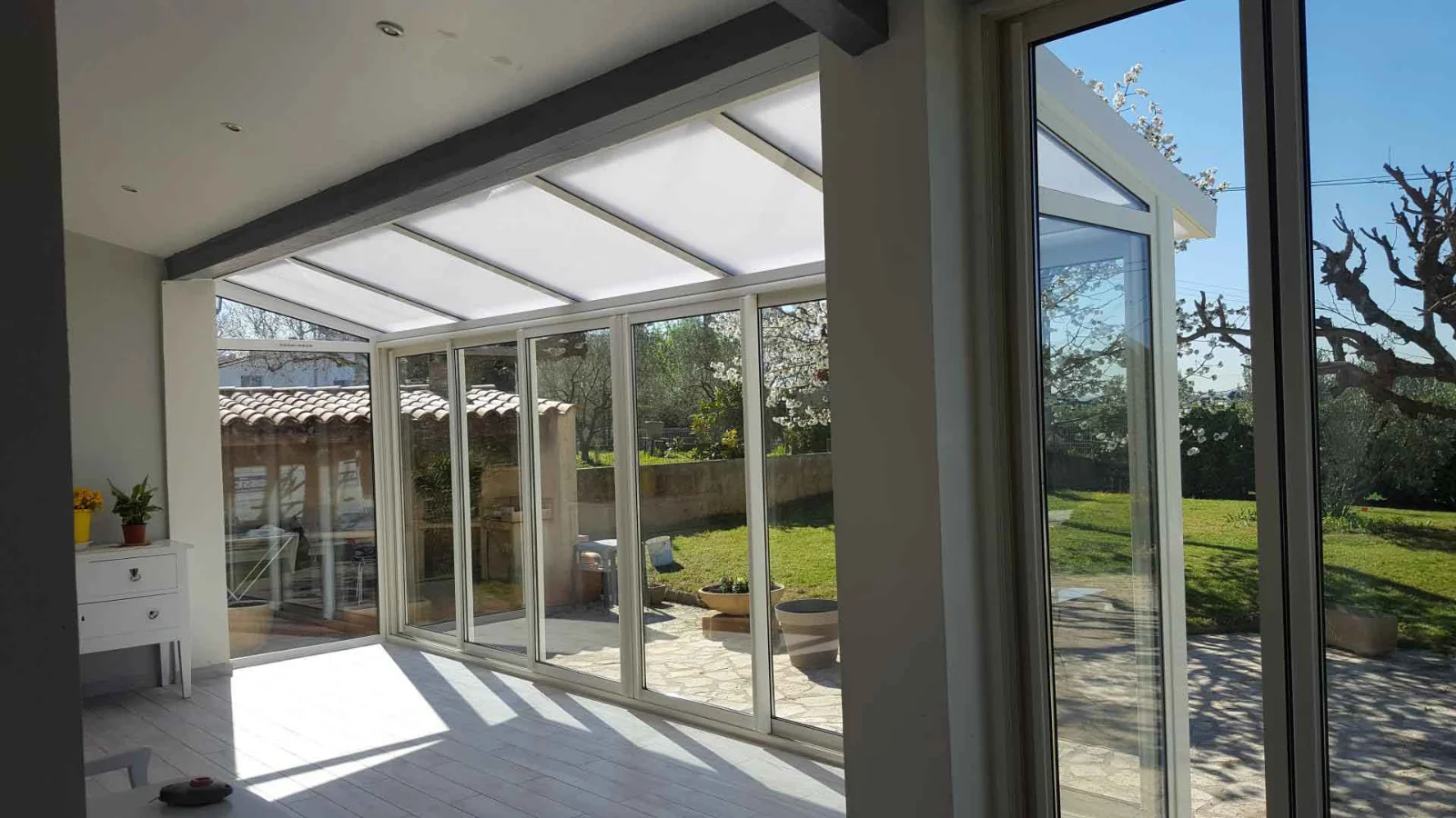 Intérieur d'une véranda aluminium ouverte sur le jardin