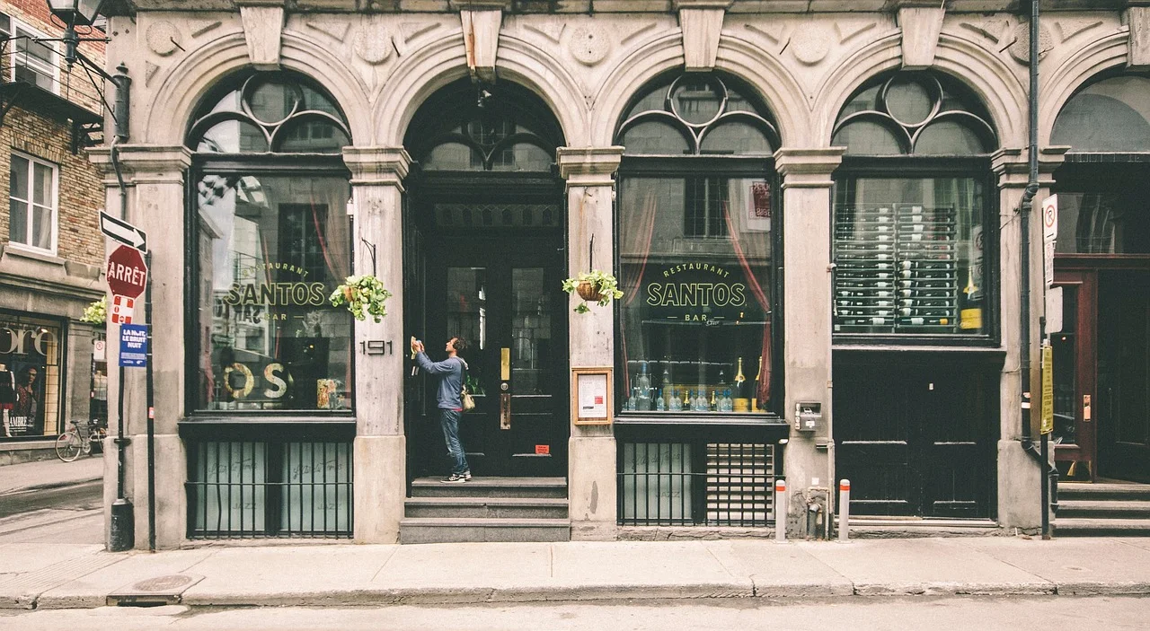 Façade de commerce en pierre avec de grandes vitrines en menuiserie noire