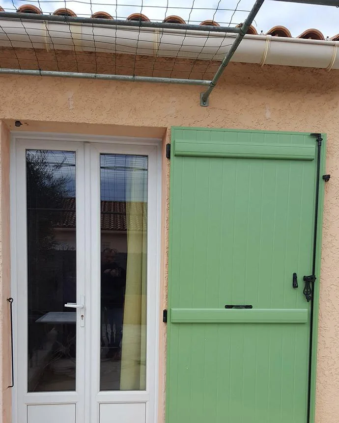 Volet battant en bois vert devant une porte-fenêtre provençale